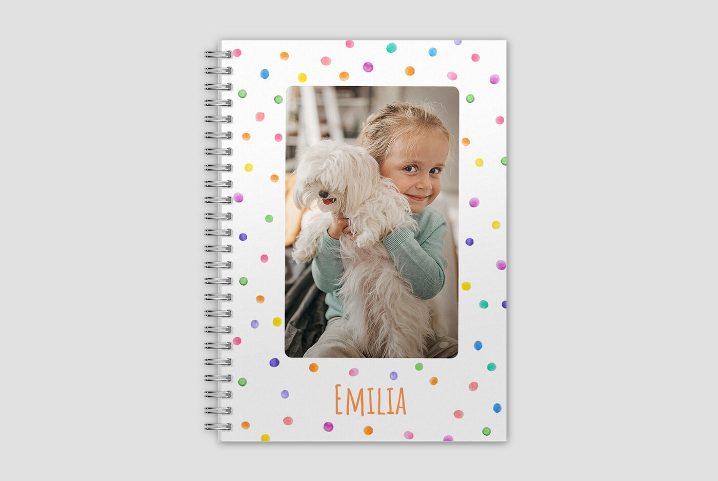 Een vrolijk kind houdt een kleine, witte hond vast in een kleurrijke, gestippelde omgeving
