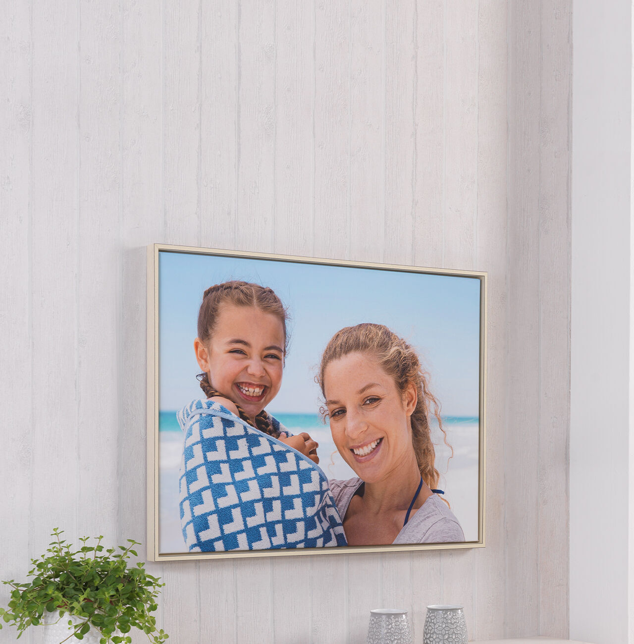 Twee mensen houden samen een handdoek vast op het strand.