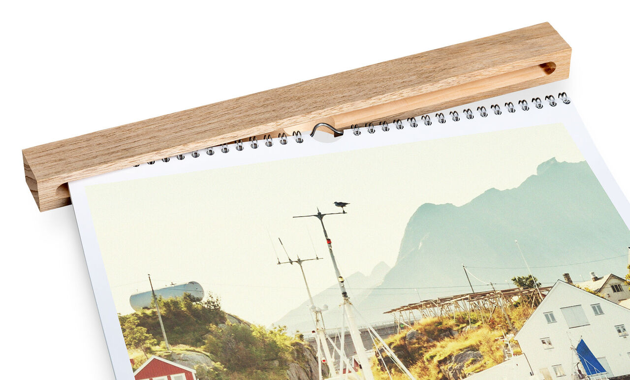 Een CEWE Fotokalender toont een schilderachtig kustlandschap met bergen zichtbaar op de achtergrond.