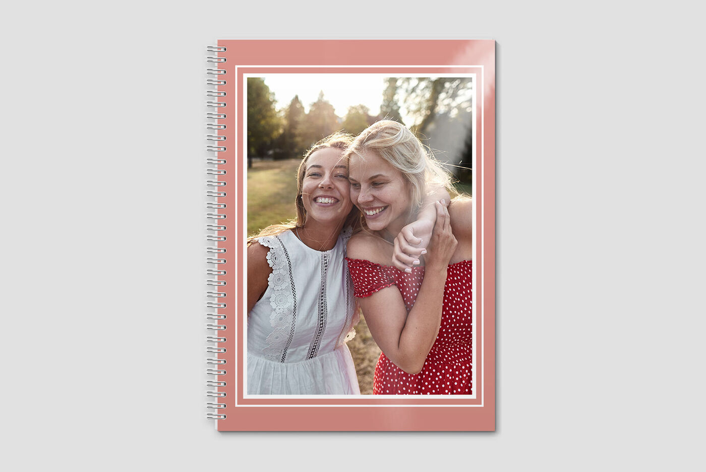 Twee vrouwen poseren in de natuur met een CEWE-fotoboek op de voorgrond