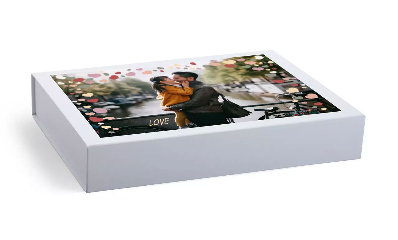 Ontworpen fotoboek met een paar dat elkaar omhelst, omringd door kleurrijke stippen en stedelijke ambiance op de achtergrond.