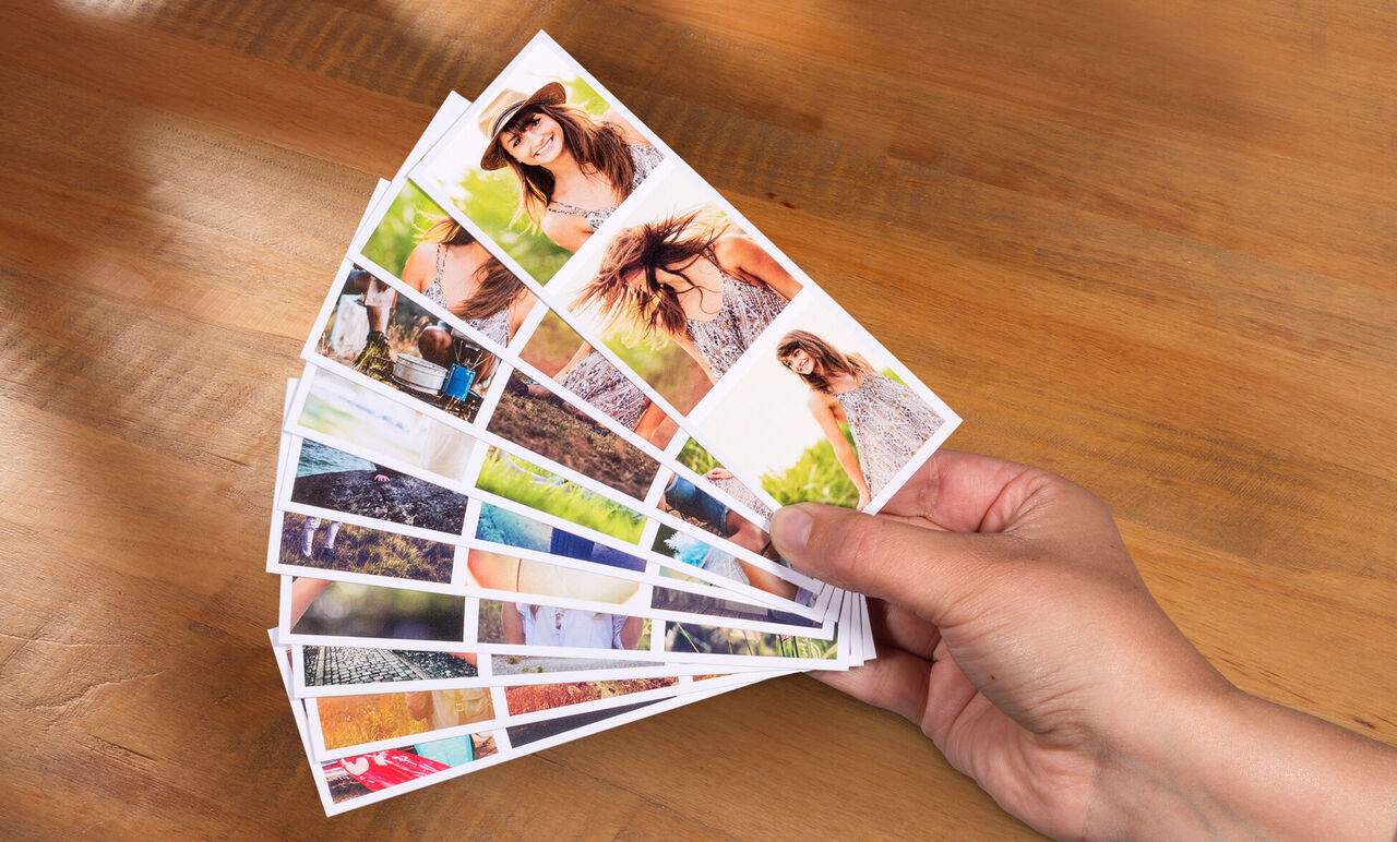 Een hand houdt meerdere foto's als een waaier vast, met mooie momenten, ideaal voor cadeautips.