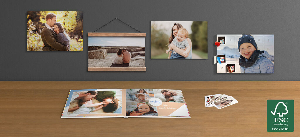 Familie toont hun CEWE FOTOBUCH met mooie herinneringen en enkele foto's aan de muur