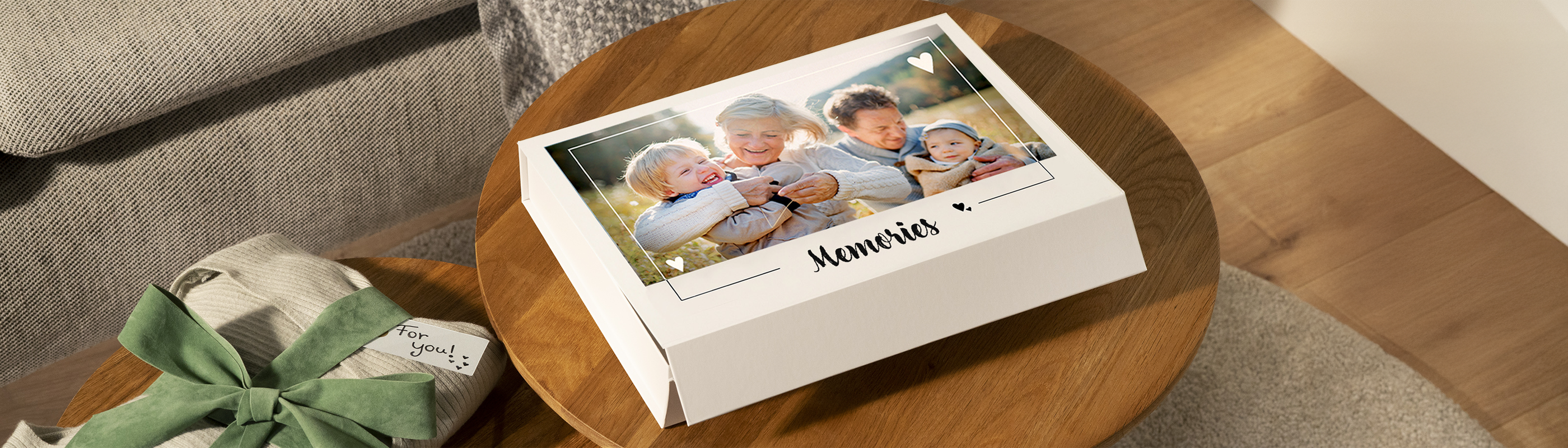 Er staat een fotogeschenkbox op de salontafel met een foto van een lachend gezin in de natuur met het woord 'memories' eronder afgedrukt.