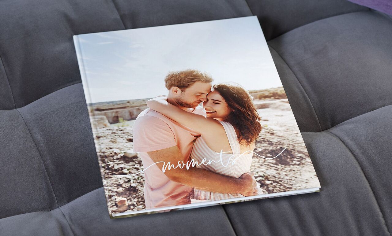 Een liefdevol fotoboek getiteld 'Momenten' toont een omhelzing. Het geeft een gevoel van nabijheid en bijzondere herinneringen.