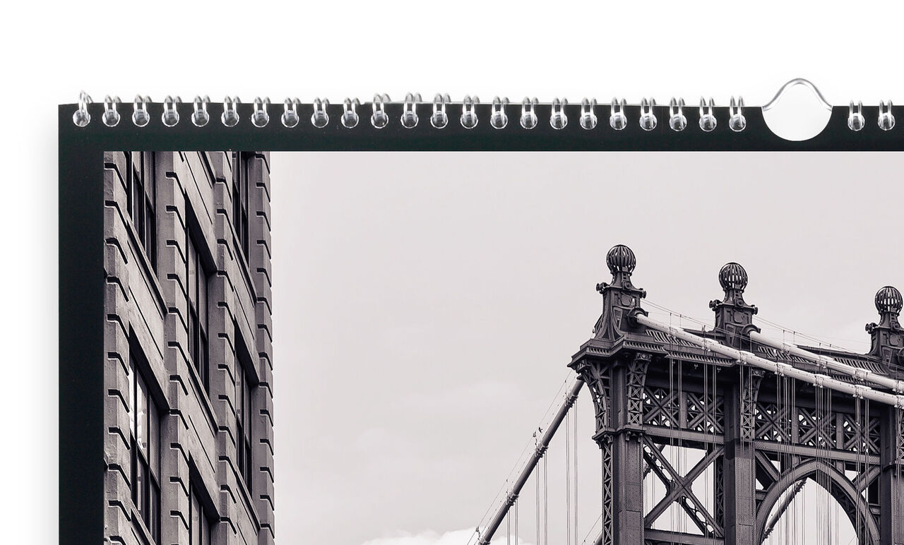 Een hoogwaardige CEWE Fotokalender toont een zwart-witfoto van de Brooklyn Bridge met een gebouw op de voorgrond.