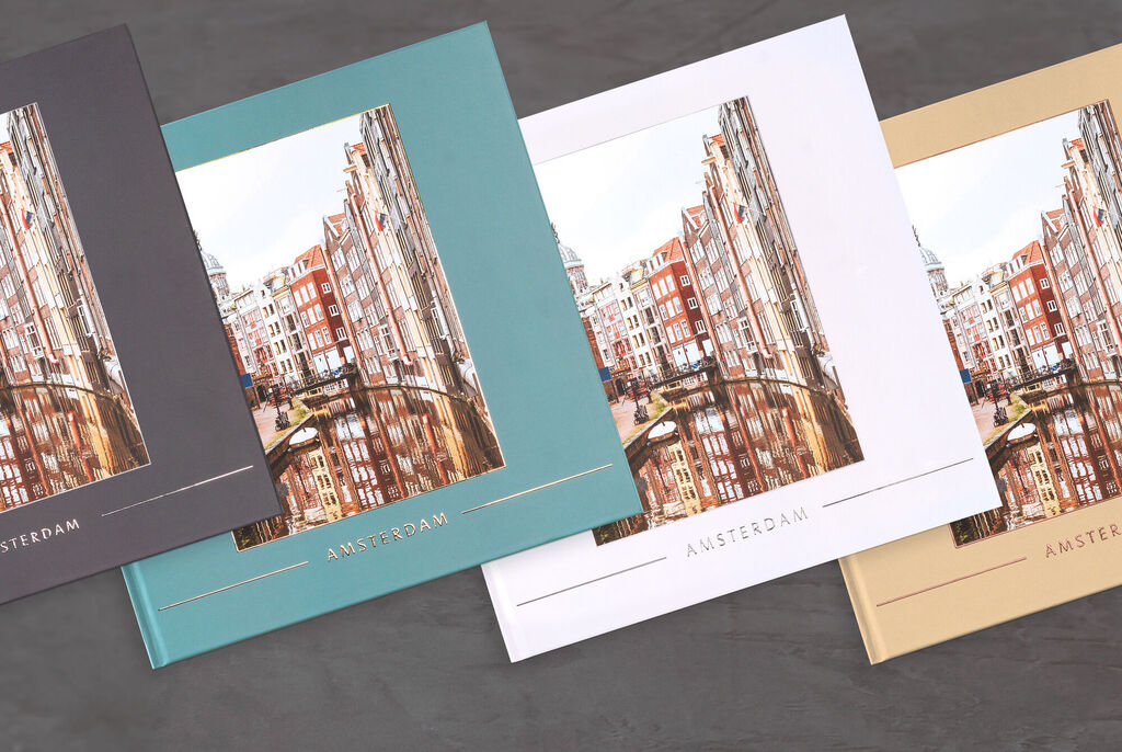 Drie CEWE Fotoboeken in verschillende kleuren met de titel 'Amsterdam', elegant gerangschikt.