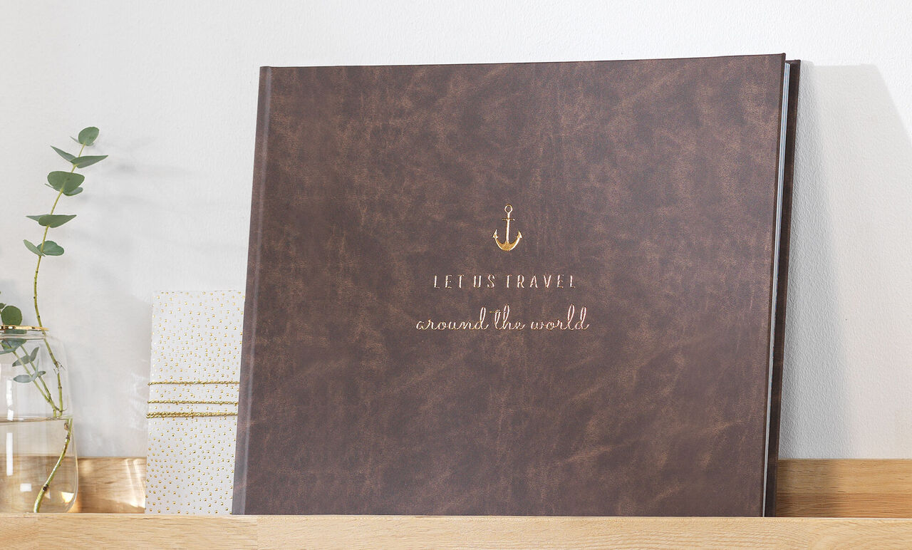 Een hoogwaardig fotoboek met de titel 'Jeremy's Travel around the world' in bruin lederen design op een plank.