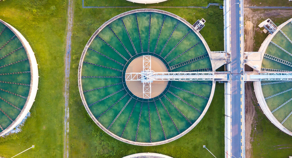 Luchtfoto van ronde watertanks in een groene omgeving.