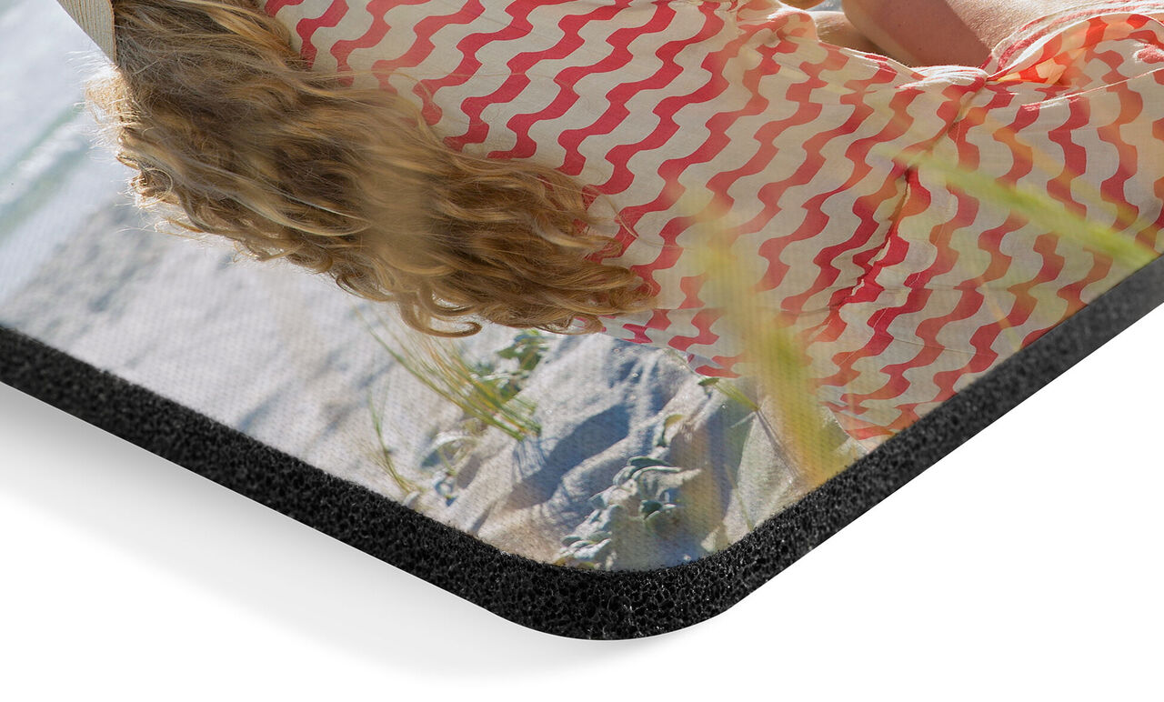 Detail van een fotoboek met kleurrijke zijkant en een foto van een vrouw op het strand.