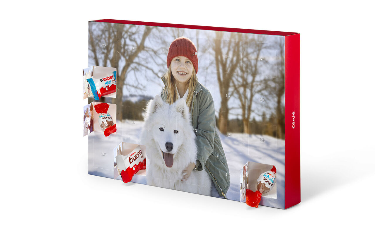 Iemand rijdt op een witte hond in de sneeuw, omringd door rode CEWE-verpakkingen.