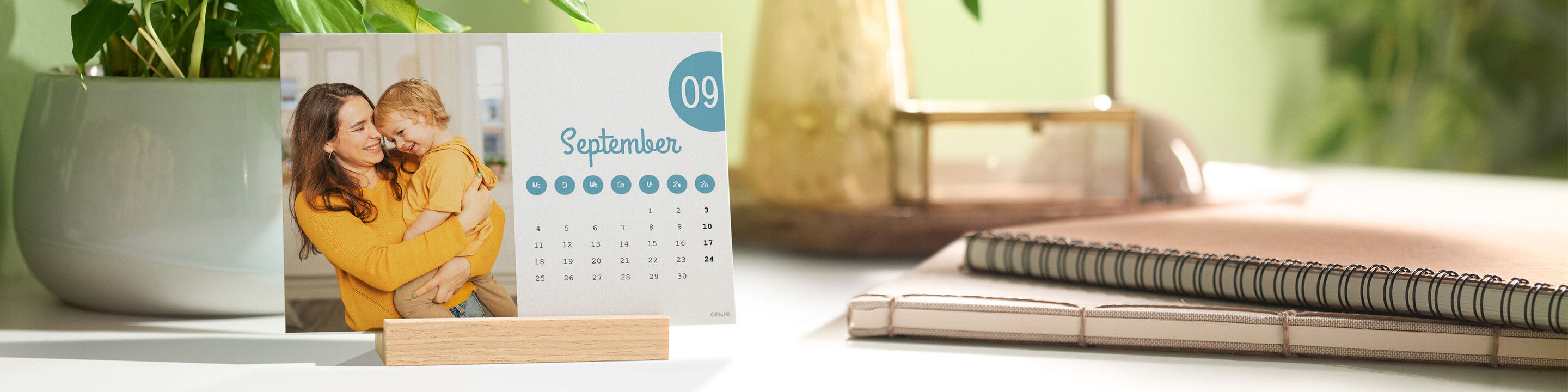 Een bureaukalender met een foto van moeder met kind staat op een bureau in een houten standaard.
