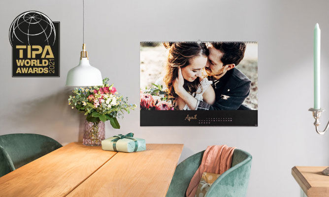 Een mooie fotokalender hangt aan een muur, omringd door bloemen en een kaars.