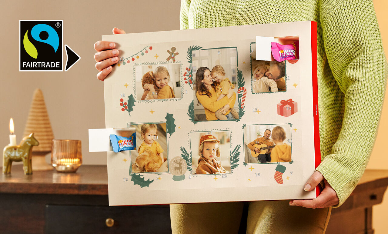 Een persoon houdt een mooie fotokalender met feestelijke beelden en decoratie vast.