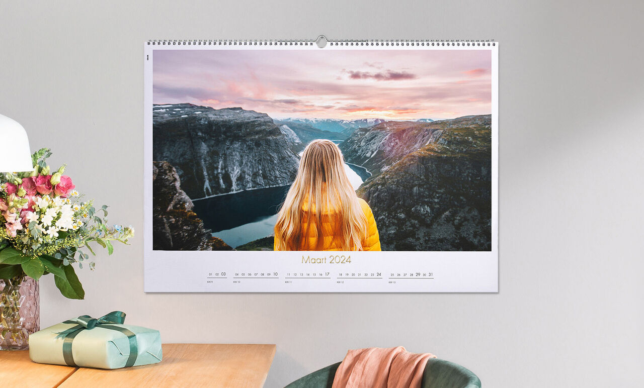 Vrouw met blond haar in gele jas kijkt naar landschap met fjord en bergen bij zonsondergang.