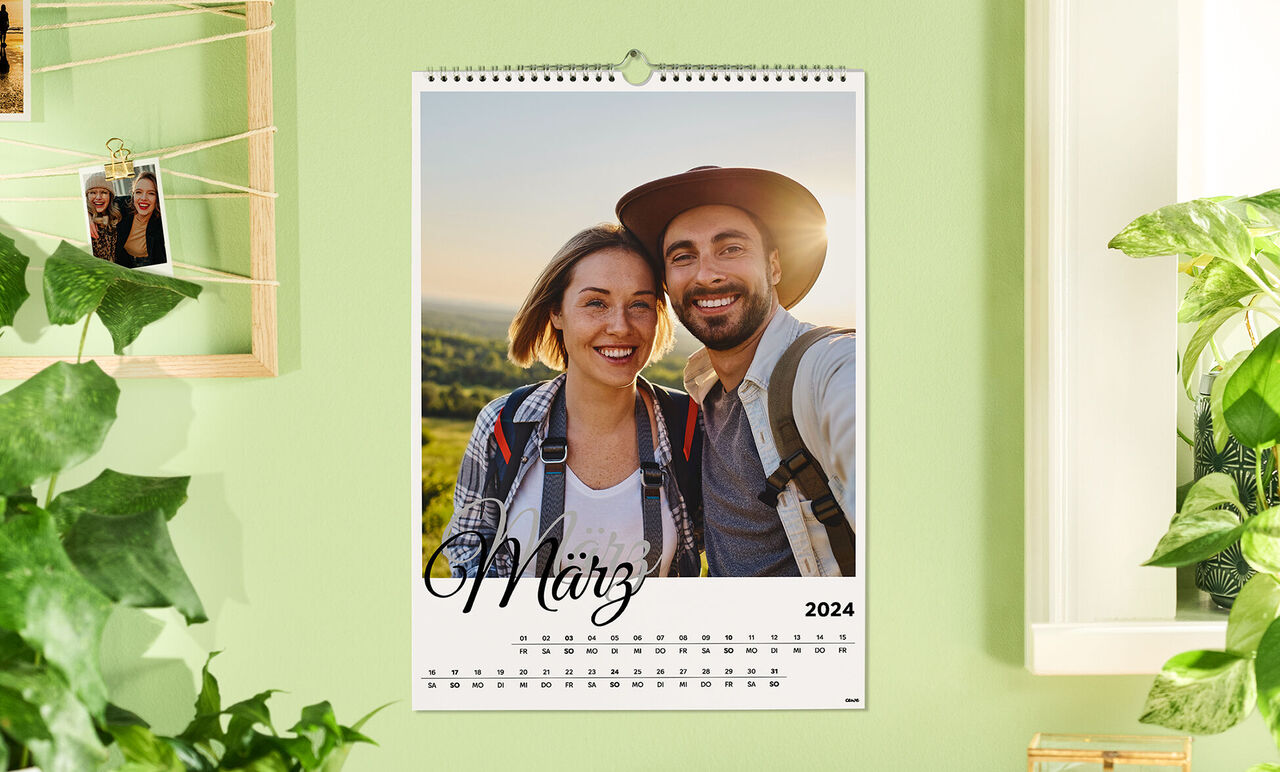 Een wandkalender voor maart 2024 met een romantische foto van twee mensen voor een groen landschap.