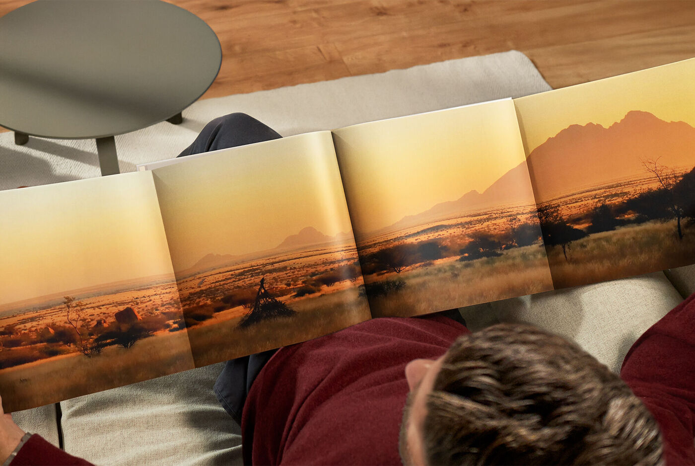 Iemand bladert door een CEWE FOTOboek met zonsonderganglandschappen.