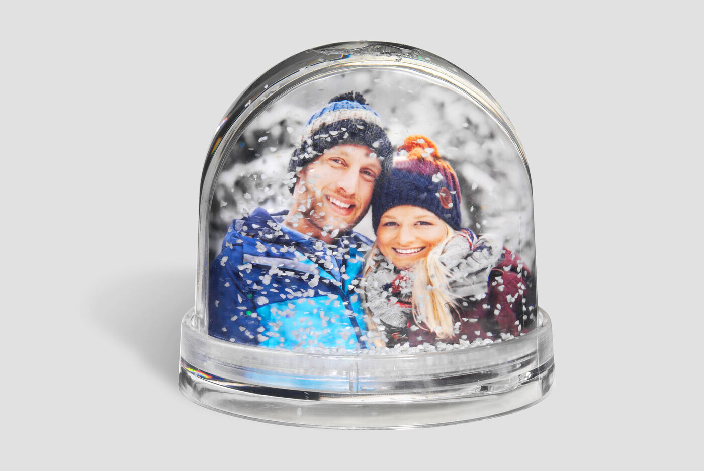 Twee mensen in een sneeuwbol, omringd door sneeuwvlokken.