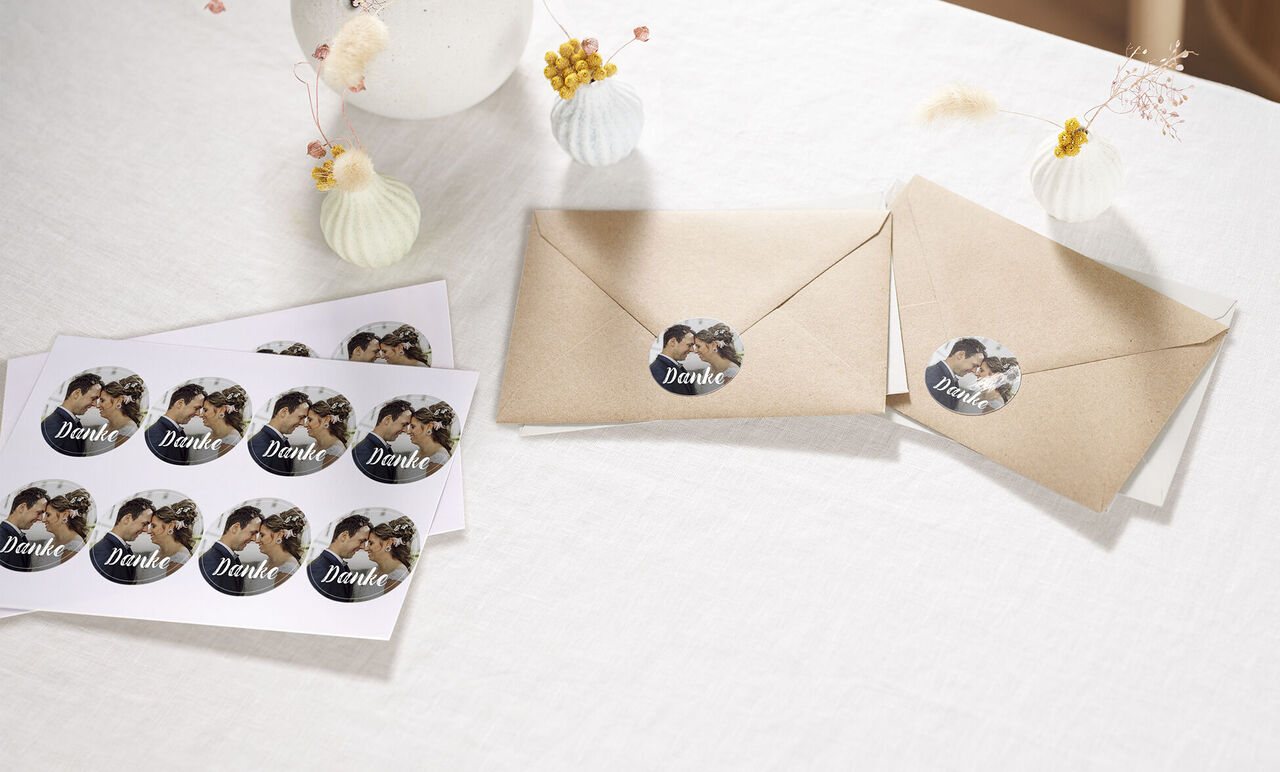 Twee beige enveloppen met bedankt-stickers en een gedrukte kaart erop