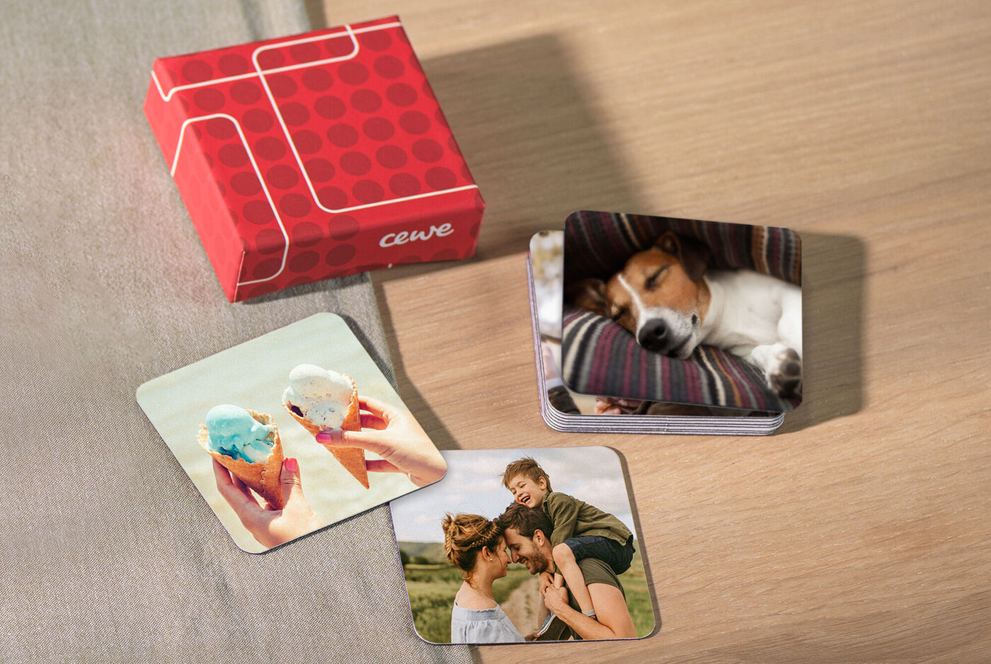 Twee fotokaarten liggen op een tafel naast een CEWE cadeauverpakking die uitnodigt tot geven.