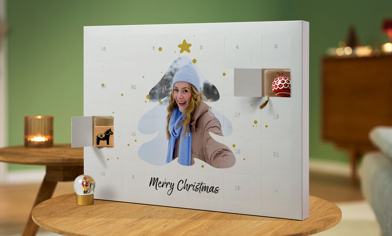 Een geopende adventkalender in de vorm van een kerstboom met cadeaus en de tekst 'Merry Christmas'.