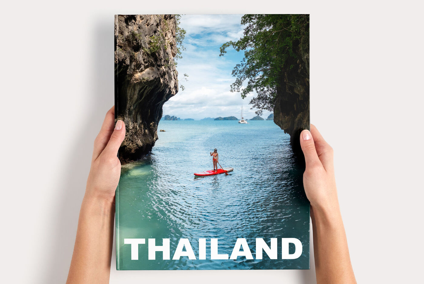 Fotoboek XXL Staand met een coverfoto van kajakken in Thailand, vastgehouden door twee handen.