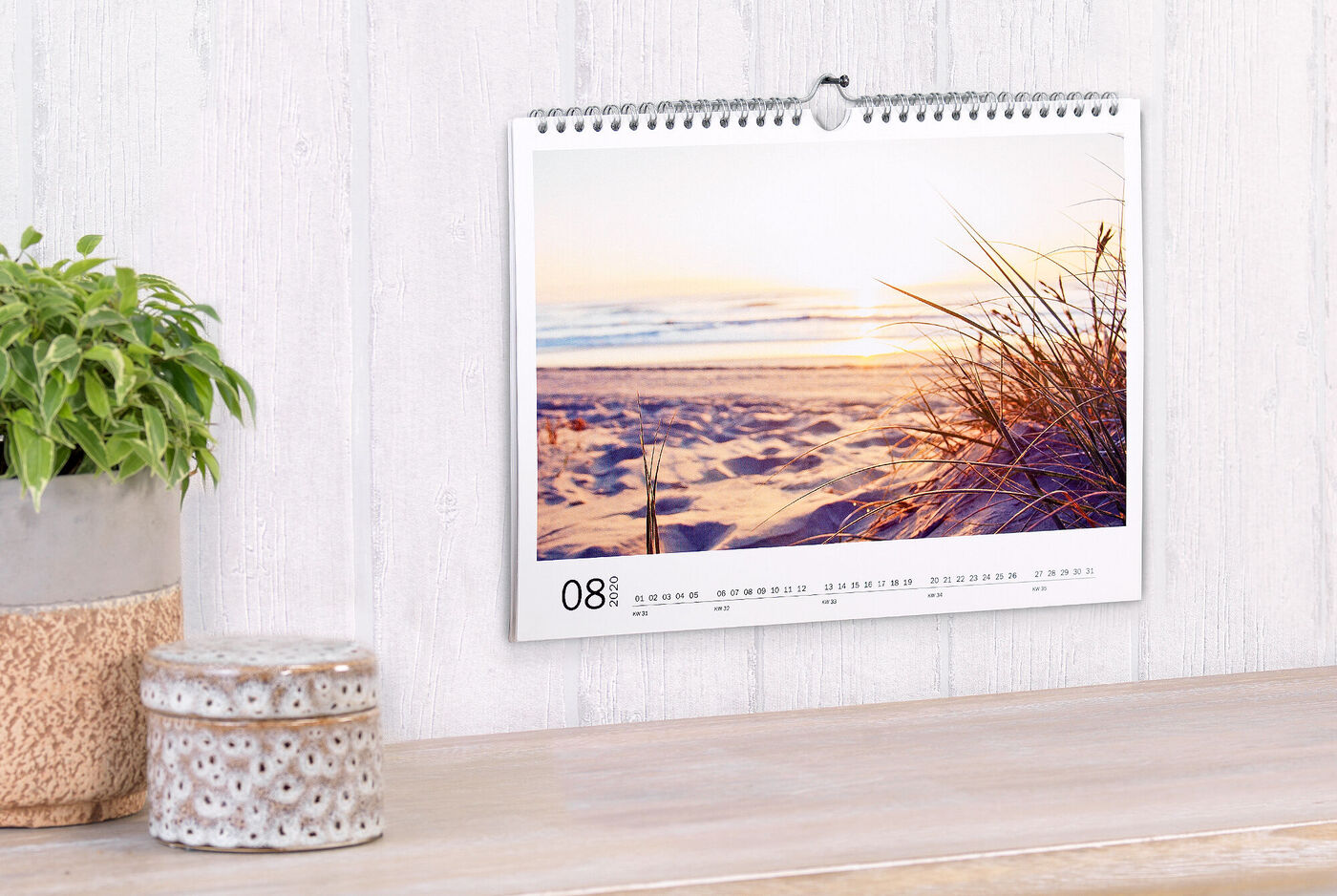 Een mooie kalender met een zonsondergang op het strand en zachte grassen op de voorgrond.