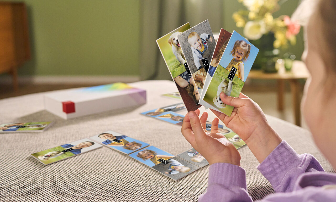 Een kind houdt liefdevol kaarten vast met familiefoto's en kleurrijke motieven.