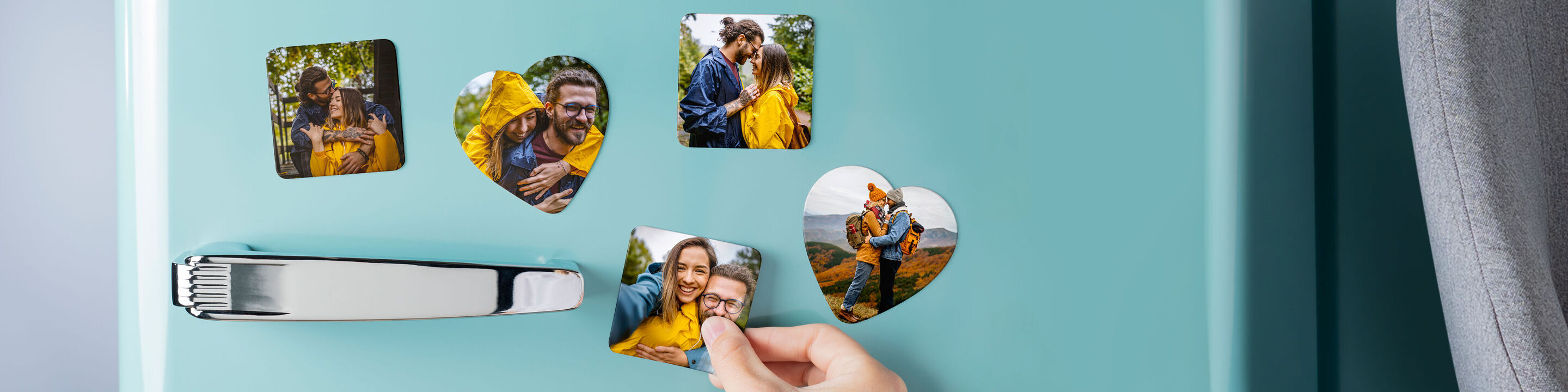 Persoon plaatst hartvormige fotomagneten met favorieten op een blauwe koelkastdeur.