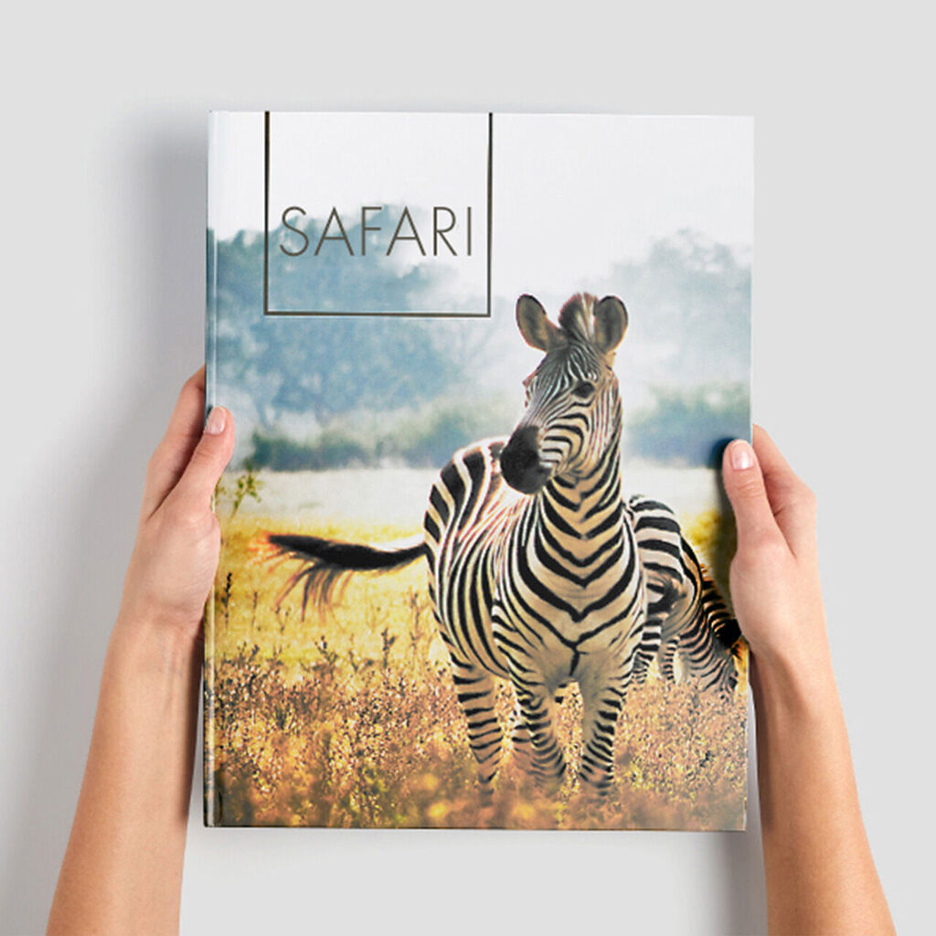 Een nieuwsgierige zebra kijkt naar de camera op de cover van een fotoalbum genaamd 'SAFARI'.