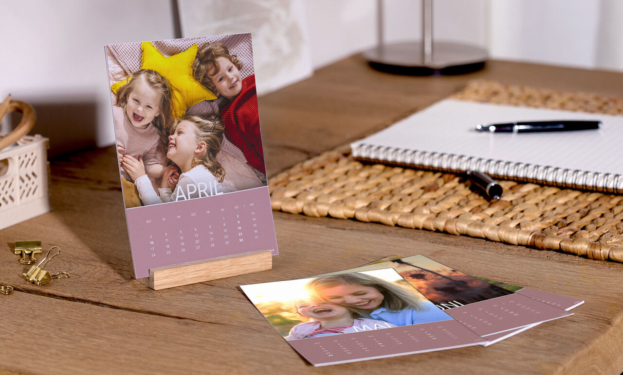 Kleurrijke tafel met een CEWE-fotokalender, foto's vol gelukkige momenten en zoete herinneringen.