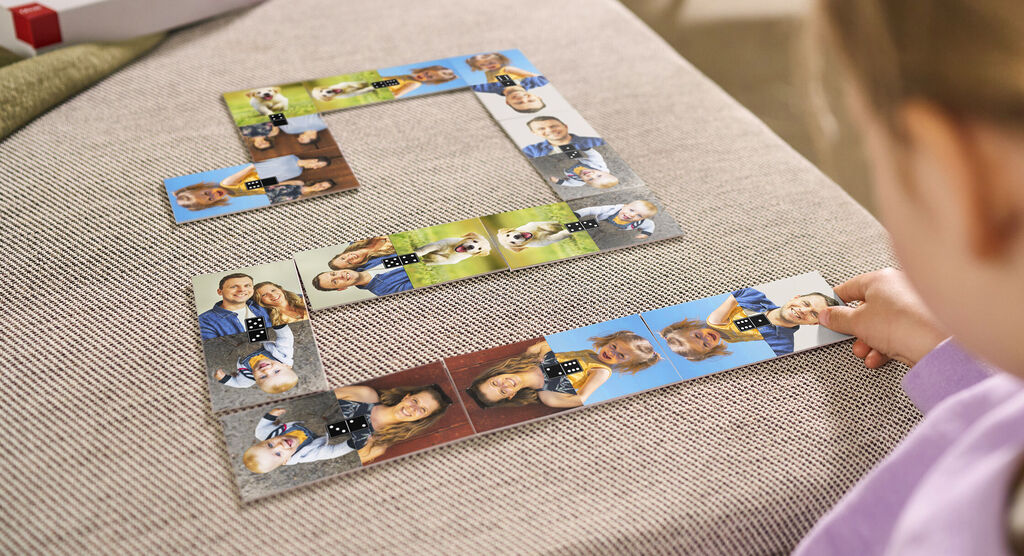 Een kind speelt met een gepersonaliseerde fotopuzzel van gelukkige momenten. Het ligt op een lichte bank.