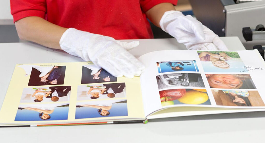Iemand bladert door een CEWE fotoboek met mooie herinneringen terwijl ze handschoenen draagt.