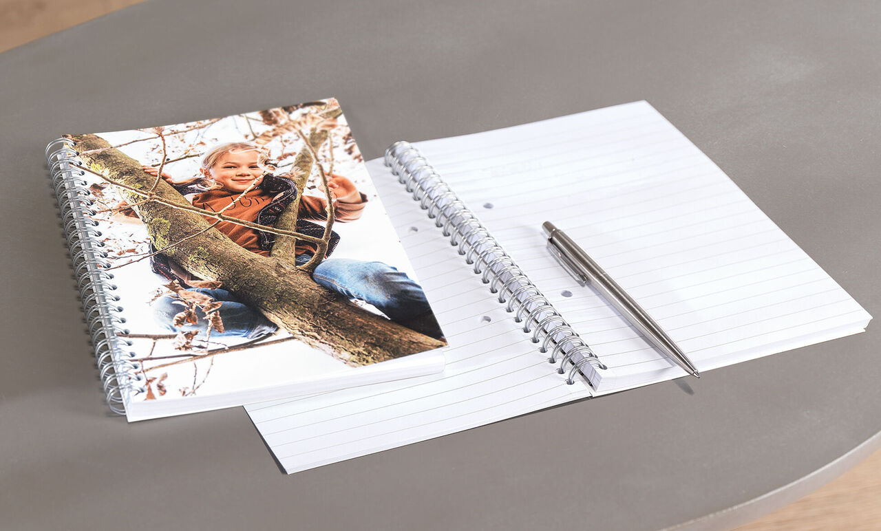 Een CEWE-fotoboek met kinderfoto en een leeg notitieboek.