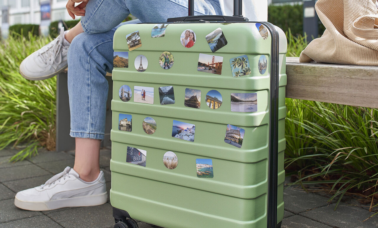 Groene reistas met herinneringsstickers op een bankje.