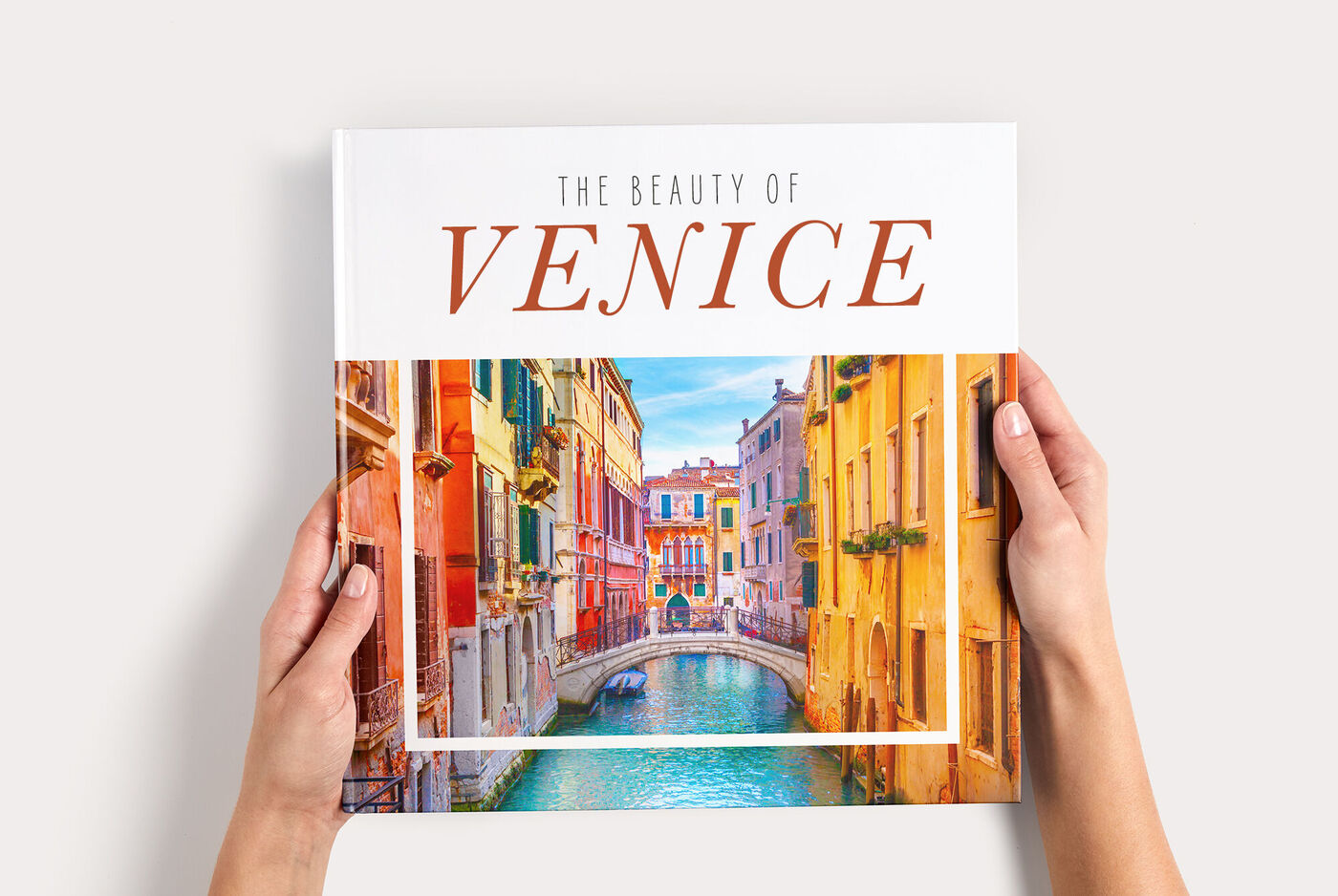 Fotoboek XL met een kleurrijke cover van Venetië en de tekst “The beauty of Venice”, vastgehouden door twee handen.