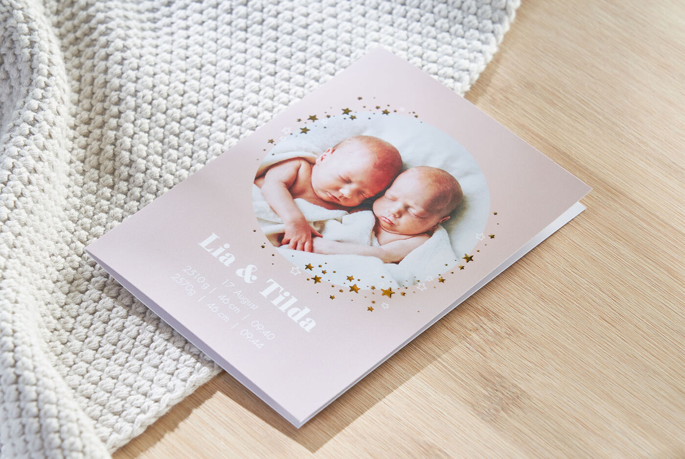 Un délicat livre photo avec les noms Lia et Tilda sur la couverture. Il montre deux jumeaux endormis dans une douce couverture.
