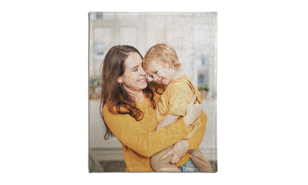 Une mère étreint son enfant, tous deux portent des couleurs chaudes