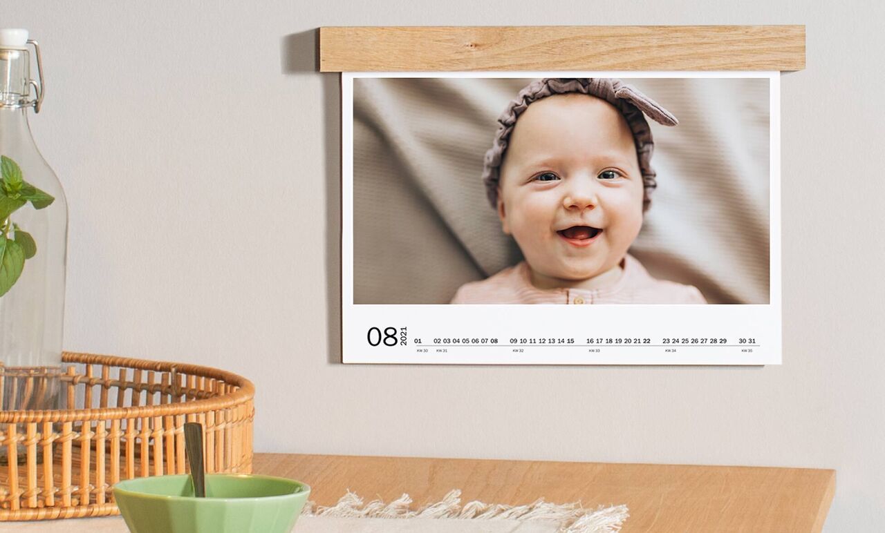 Une image montre un bébé mignon dans une robe délicate avec un joli bandeau. L'image fait partie d'un calendrier.