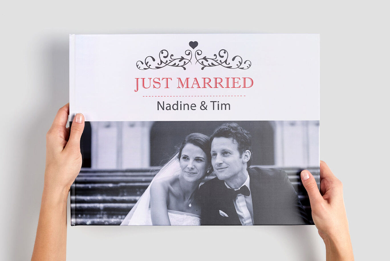 Un couple tient son album personnel "Just Married" avec les noms Nadine et Tim.