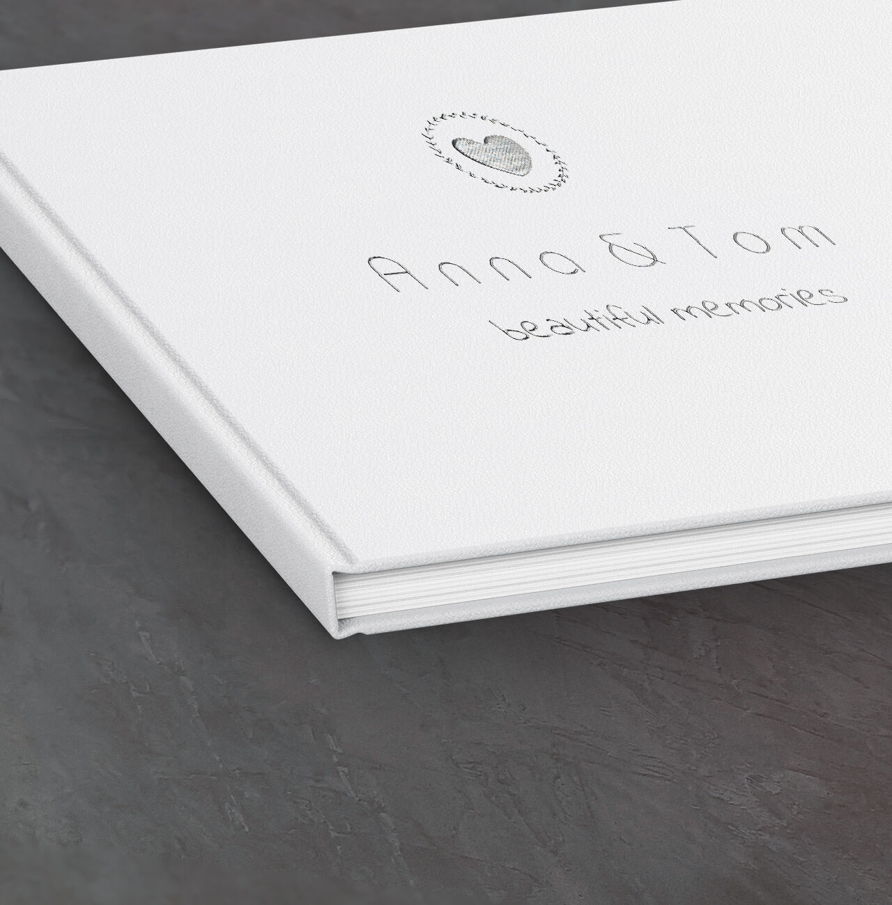 Album photo blanc avec le titre 'Anna & Tom - souvenirs' sur une table sombre.