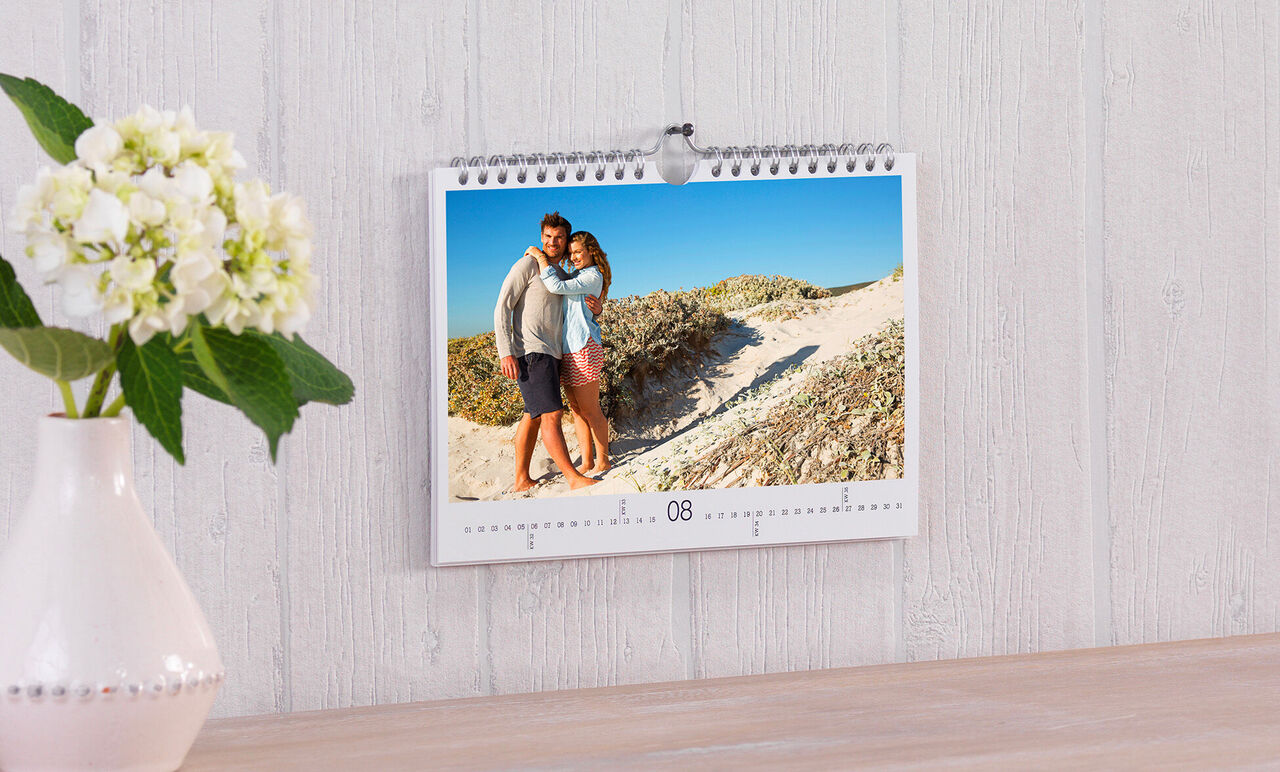 Un couple s'embrasse joyeusement devant une plage de sable dans un calendrier photo