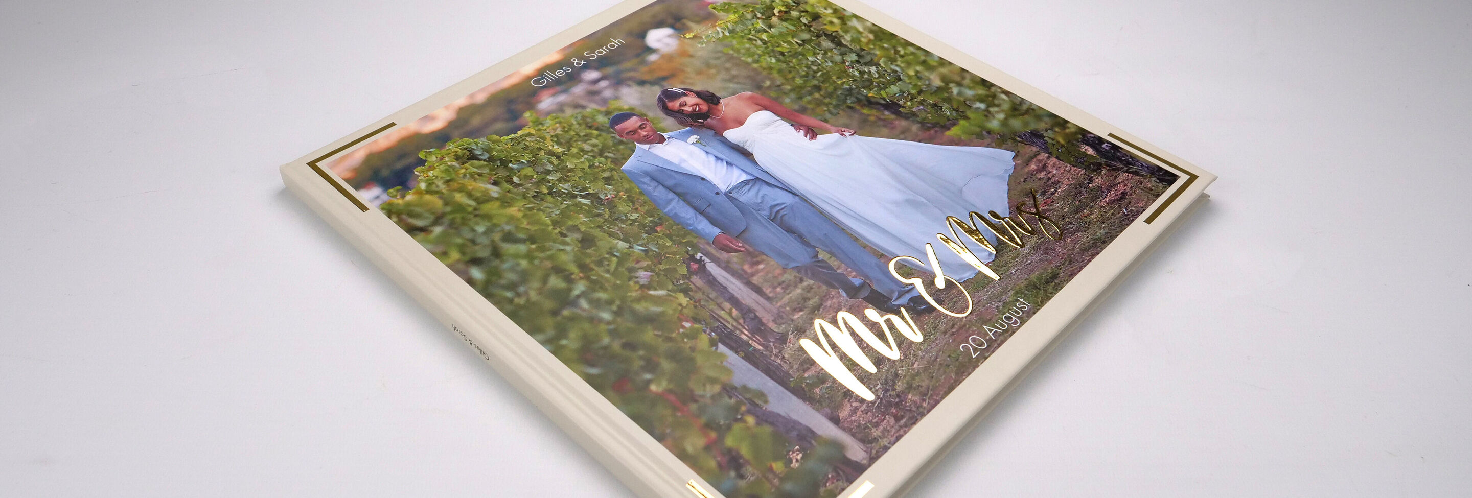 Un CEWE FOTOBUCH élégant avec le titre 'Mr & Mrs' sur une table entourée de vignes.