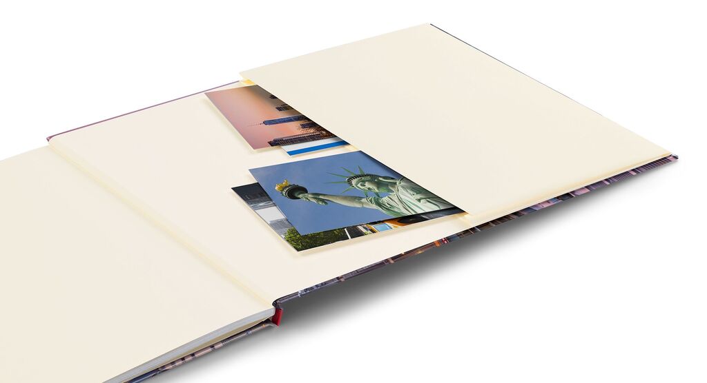 Un livre photo CEWE ouvert avec des pages beige, montrant plusieurs photos dont la statue de la Liberté.