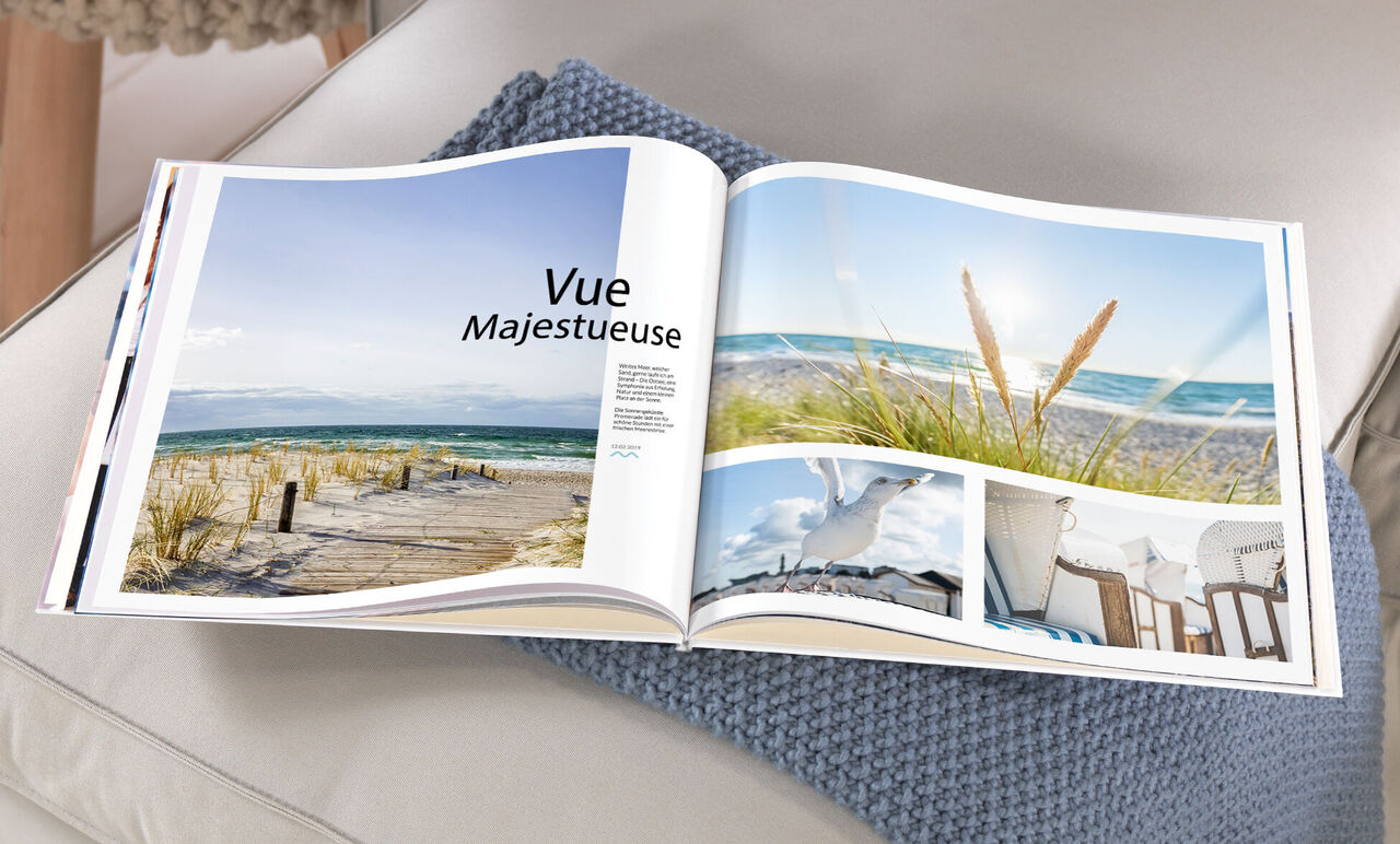 Un livre photo CEWE ouvert montre des souvenirs de vacances magnifiques à la plage sous un ciel bleu.