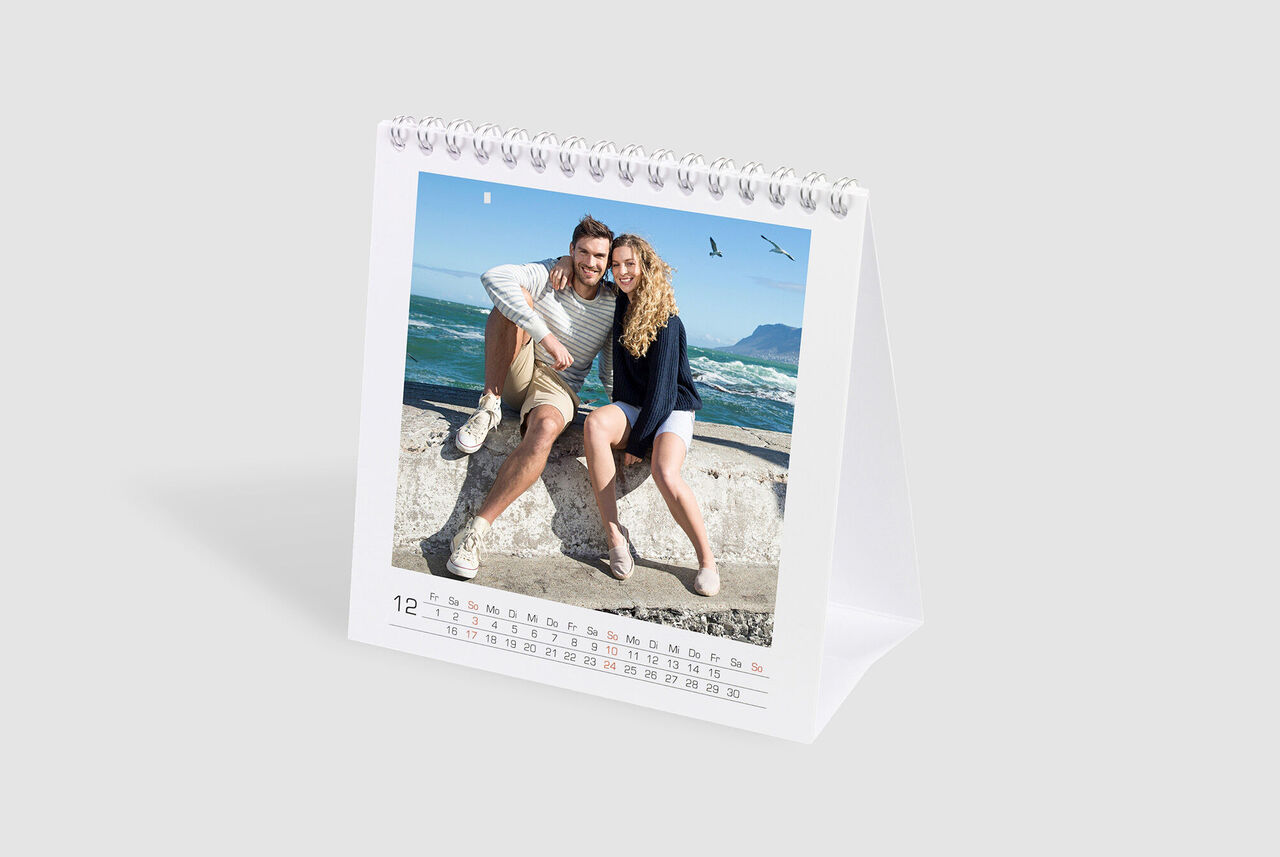 Un calendrier est sur une table montrant une image d'un couple heureux à la plage.