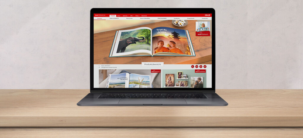 Un ordinateur portable avec le site CEWE FOTOBUCH ouvert sur une table en bois