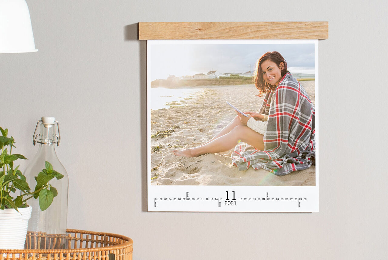 Calendrier mural avec un mois et une personne assise sur une plage.