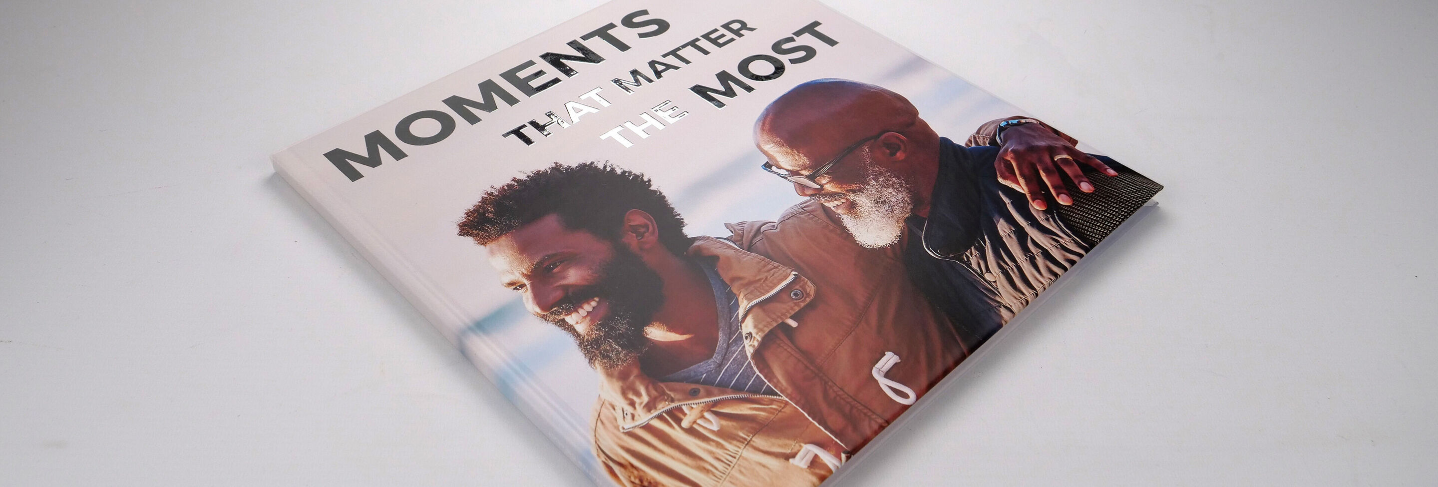 Un livre photo CEWE avec le texte 'Moments That Matter Most', montrant deux individus partageant un moment heureux.