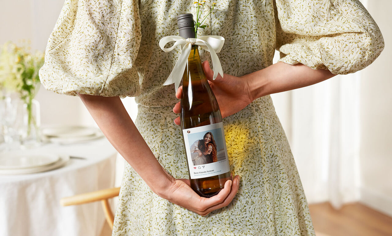 Une personne tient une bouteille de vin avec une étiquette personnalisée.